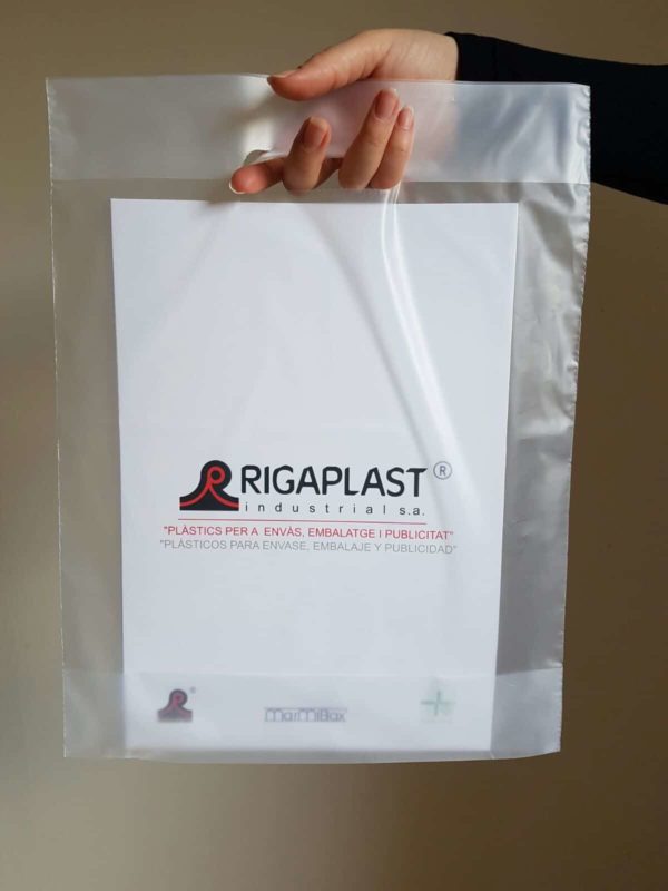 Sujetando una bolsa de plástico con asa tipo troquel y logo rigaplast. Se pueden personalizar